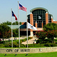 City of Hurst courthouse with flags flying in front of building.