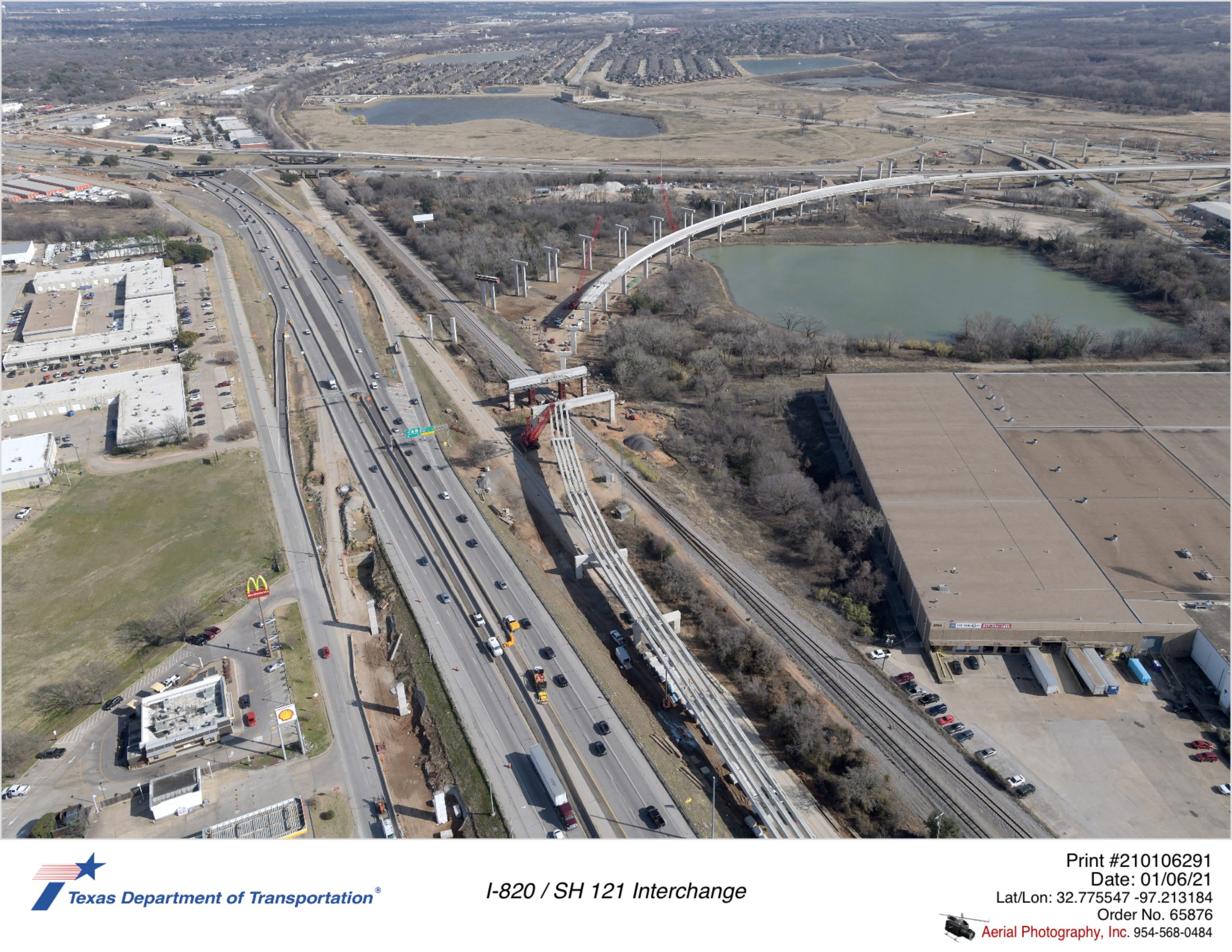 SH 121 looking northeast over Handley-Ederville Rd interchange. Construction of new direct connectors to I-820 crossing Trinity Rail Express are shown.