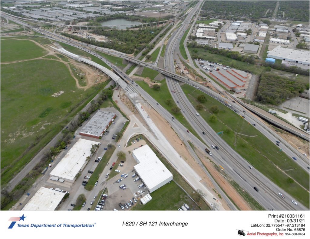 SH 121 looking southwest over I-820. Construction focus showing progress at Central Park Dr intersection with I-820 northbound frontage road, and new northbound frontage road bridge over Trinity Rail Express.